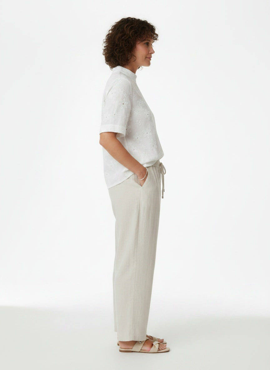 Side profile of the model wearing Witte Broderie Blouse met Opstaande Kraag