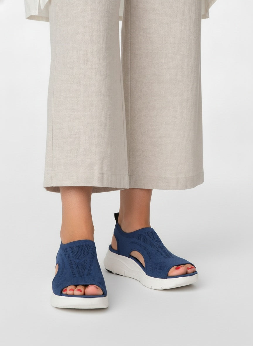 Close-up lower legs and shoes of the model wearing Orthopedische Sandalen met Sleehak en Uitsnijdingen